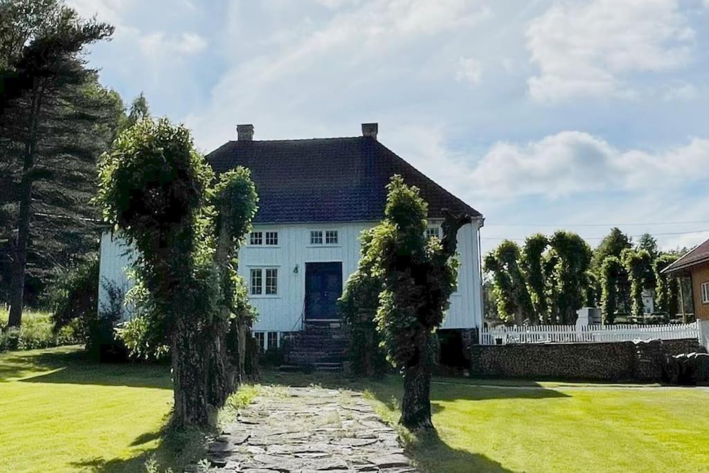 里瑟尔Bosvik Gård, nyrenovert leilighet i hovedhus fra 1756的前面有两棵树的白色房子
