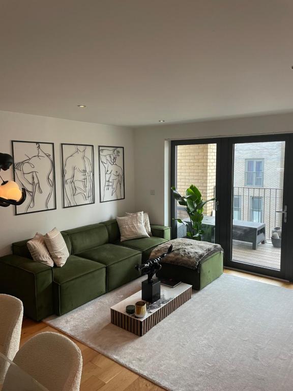 伦敦Cosy bedroom in Luxury apartment的客厅设有绿色沙发和大窗户