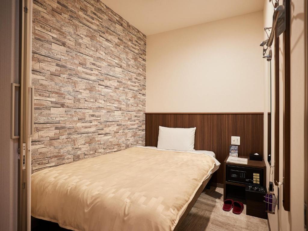 那霸Grand Cabin Hotel Naha Oroku - Vacation STAY 46864v的一间卧室设有一张床和砖墙