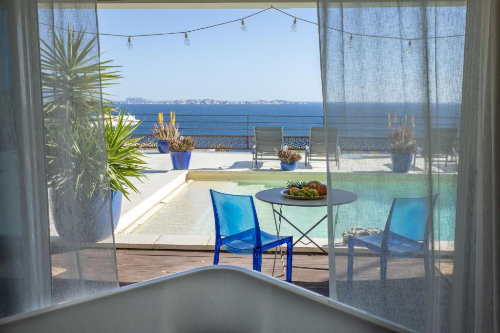 马赛LES SUITES LOVE 2 SPA VUE MER PISCINe的阳台配有桌子和2把蓝色椅子