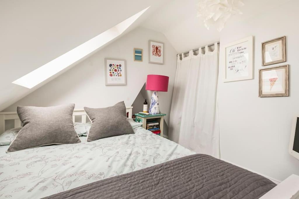 桑盖特Hideaway Cottage - seaview room with shared bathroom的白色卧室配有床和粉红色灯