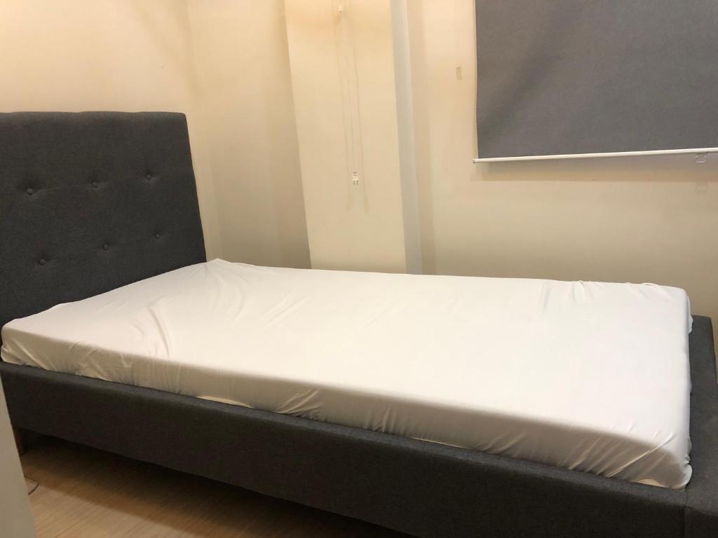 马尼拉Comfy Room With Single Sized Bed, Study Space, Closet, and WiFi的一张位于黑床架的房间的床位