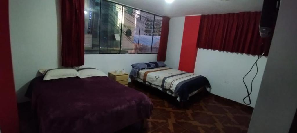 万卡约Hotel Águila Real的红色和白色墙壁的客房内的两张床