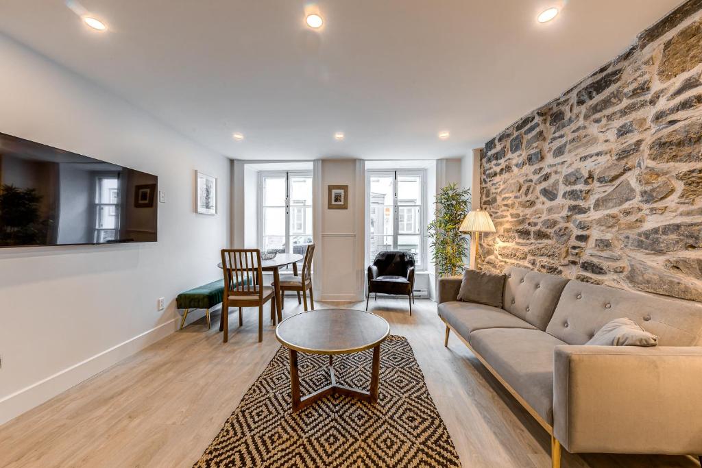 魁北克市Elegant 1 Bedroom Suite的带沙发和石墙的客厅