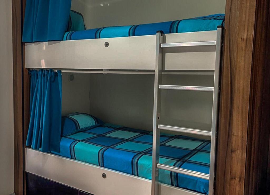 利物浦The Liverpool Pod Travel Hostel的两张双层床,配有蓝色床单和梯子