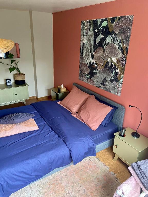 韦姆Champagne的卧室配有一张蓝色的床,墙上挂着一幅画