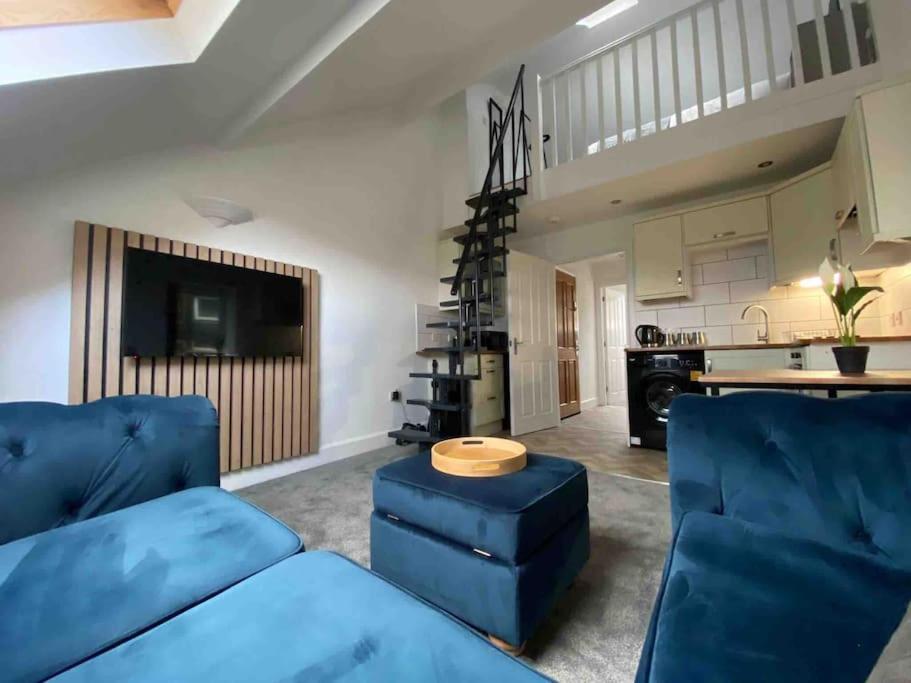 马特洛克Wards House Loft Apartment, Matlock的一间带蓝色沙发的客厅和一间厨房