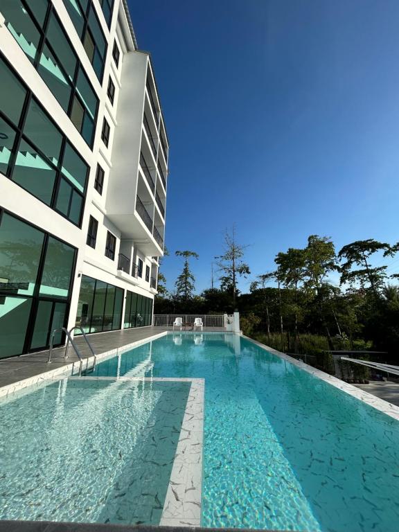 春武里GEEN Hotel Chonburi的大楼旁的大型游泳池
