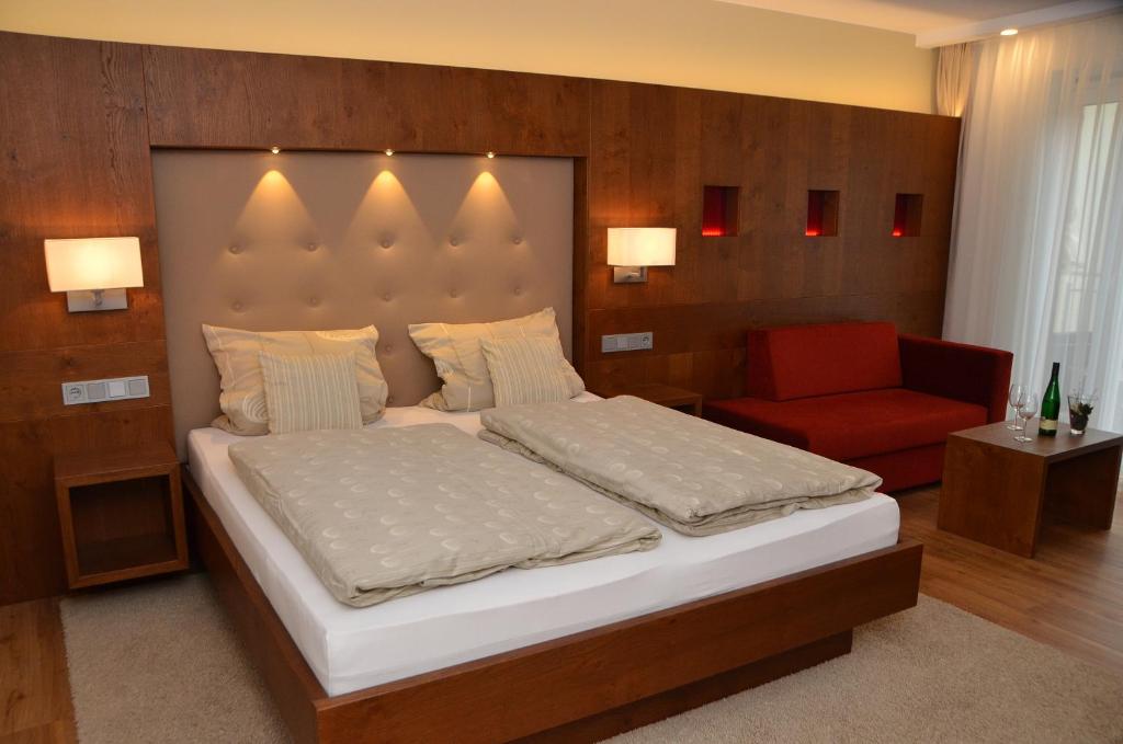 特里滕海姆赛米纳斯霍夫旅馆的一间卧室配有一张大床和一张红色椅子