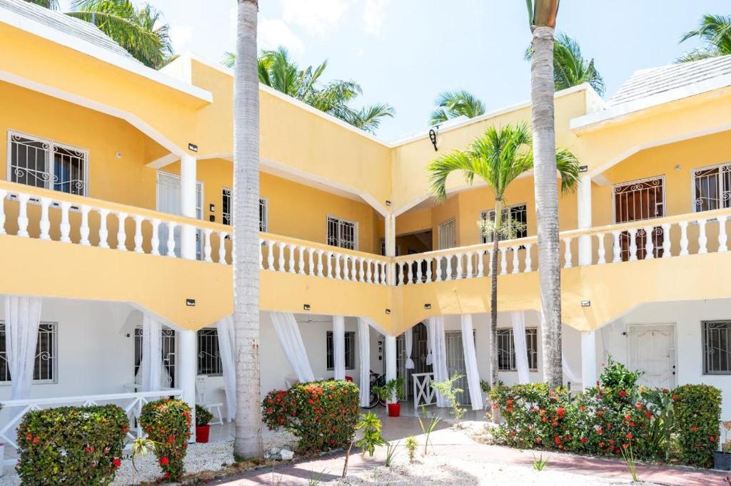 蓬塔卡纳Hermosa Suites #2 in the heart of PUNTA CANA的棕榈树和鲜花的黄色建筑