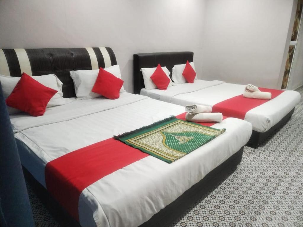 丹那拉打Ar Rayyan Hotel的两张带红色和白色枕头的床