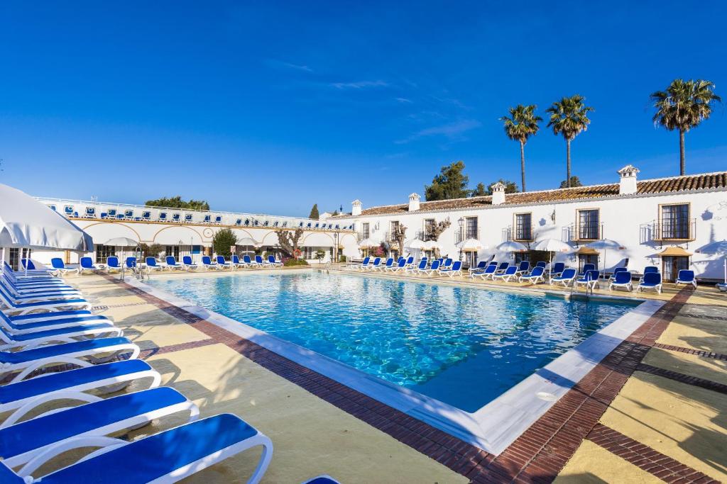 马贝拉全球科尔蒂霍布兰科酒店的一座带蓝色椅子的大型游泳池和一座建筑