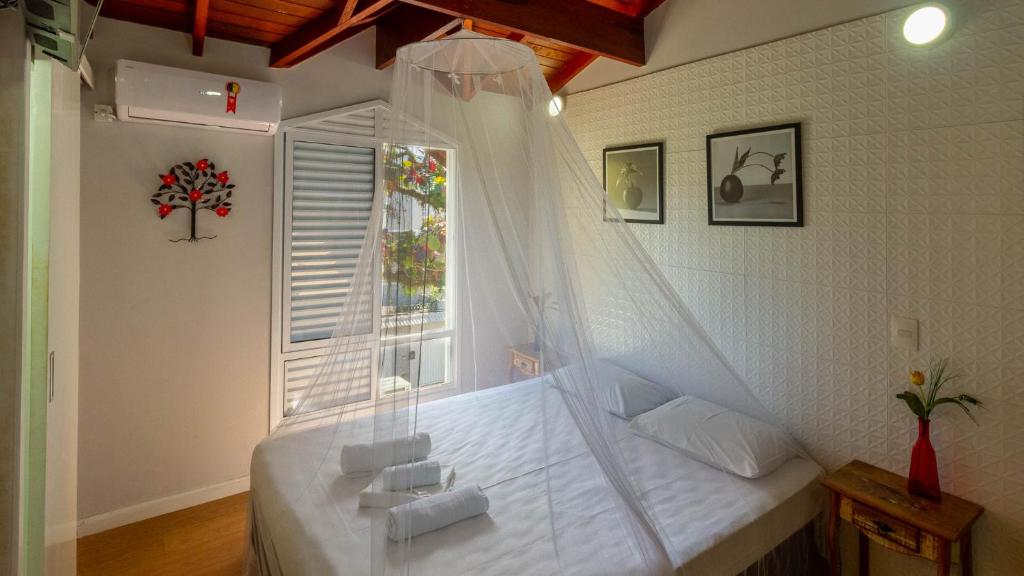 瓜鲁雅Guarujá Hostel的一间卧室配有一张天蓬床和窗户