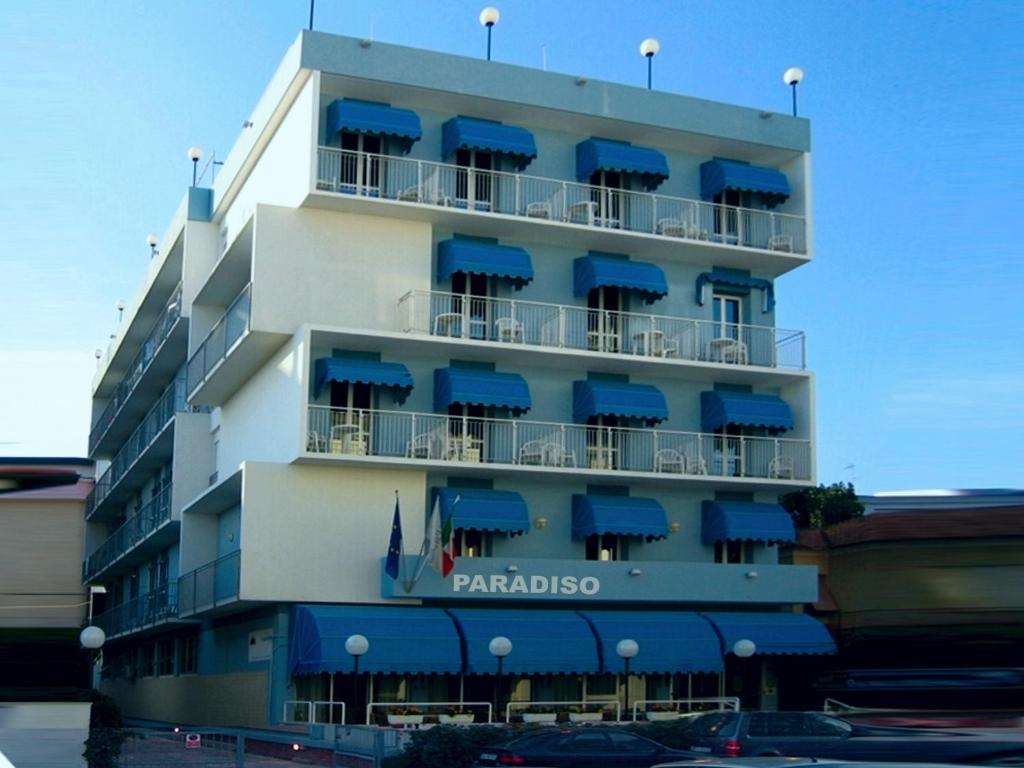 西尼加利亚Hotel Paradiso的一座高大的建筑,上面有蓝色遮阳篷