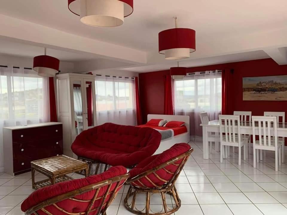 塔那那利佛Appartements Andrian Location的客厅设有红色的墙壁和一张床及椅子