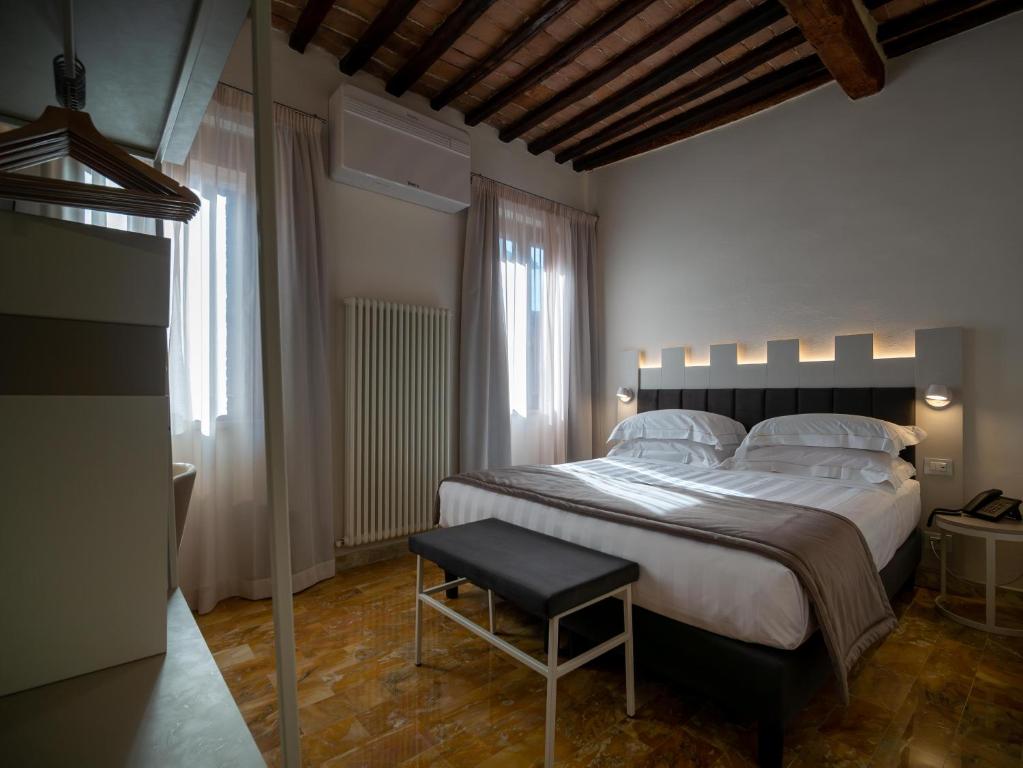 锡耶纳Torre del Fuggisole的一间卧室配有一张大床和一张凳子