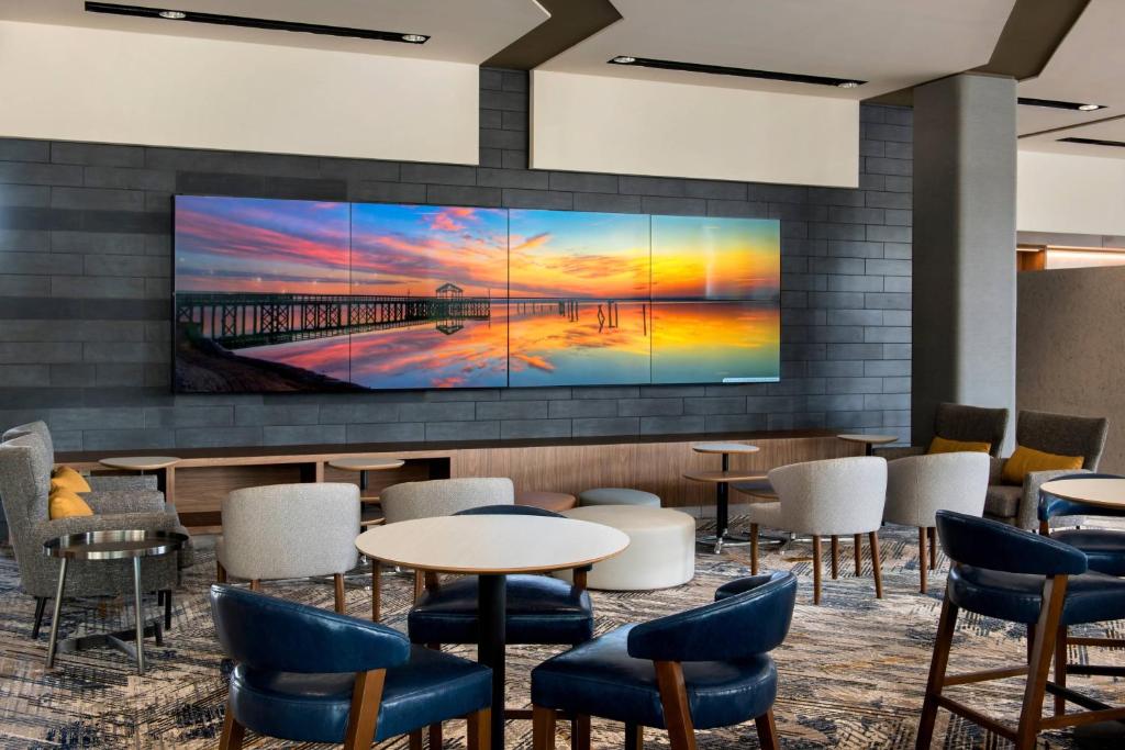 费城费城南海军船坞万怡酒店的大堂设有桌椅和大屏幕电视