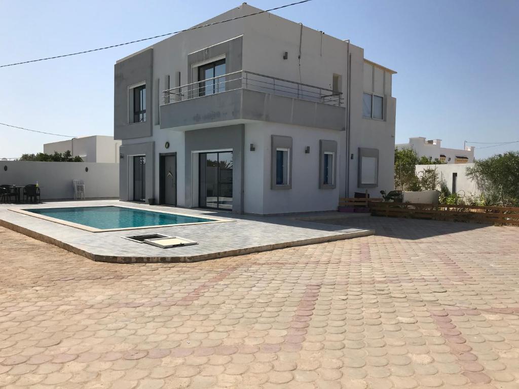 米多恩Villa privé 4 chambres 4 lit double à Djerba en face de la ferme de lotos的一座房子前面设有游泳池