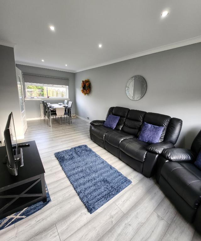 阿丁斯顿Stunning 3 bedroom FMHomes & Apartments的客厅配有黑色真皮沙发和蓝色地毯。