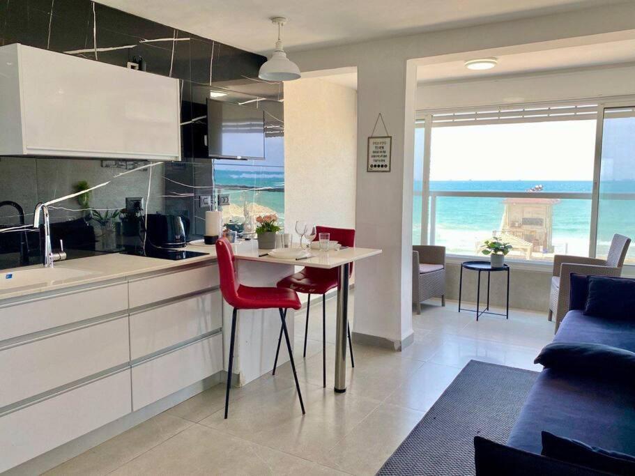 海法Seaside cozy apartment的一间厨房,里面配有桌子和红色椅子