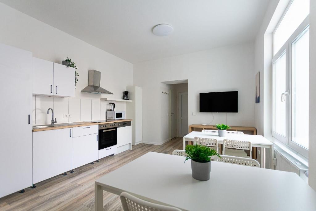 杜伊斯堡T&K Apartments - 1 to 4 Room Apartments - 20min to TradeFair Messe Airport Düsseldorf的厨房配有白色橱柜和桌椅