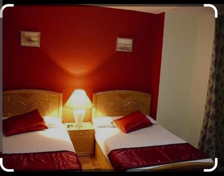 开罗Mo Hotel的红色墙壁客房的两张床