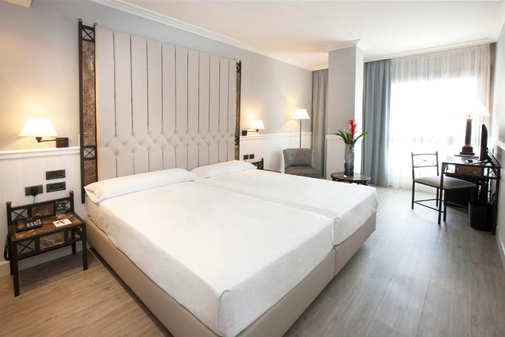 洛格罗尼奥格兰维亚酒店的卧室配有一张白色大床和一张书桌