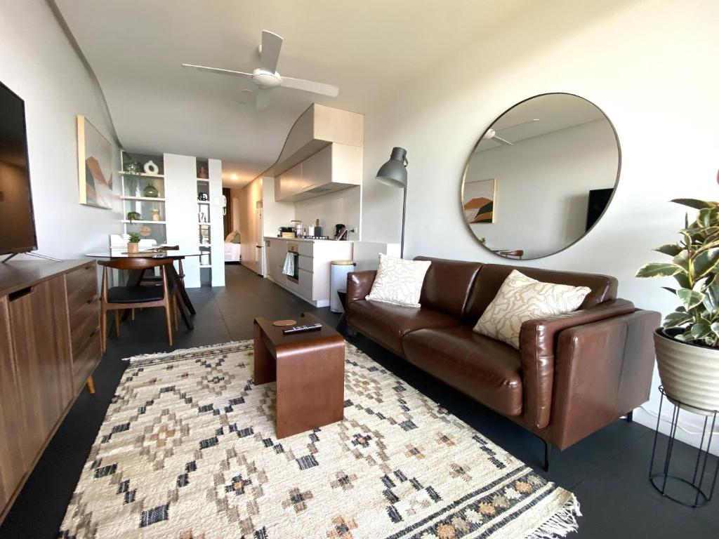 堪培拉Stylish Central Lake View Apartment的客厅配有棕色皮沙发和镜子