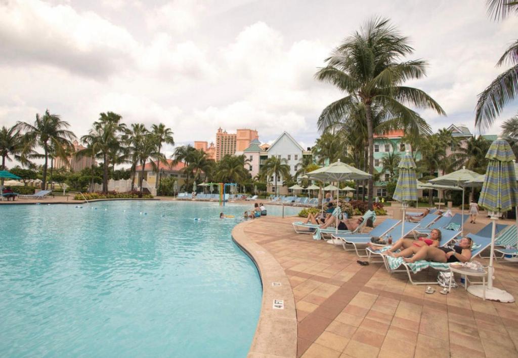 拿骚Harbourside Resort, Paradise Island Bahamas的度假村的游泳池,人们坐在椅子上