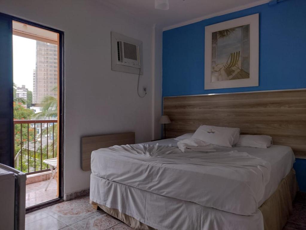 瓜鲁雅Astúrias Praia Hotel的一间卧室配有一张蓝色墙壁和窗户的床