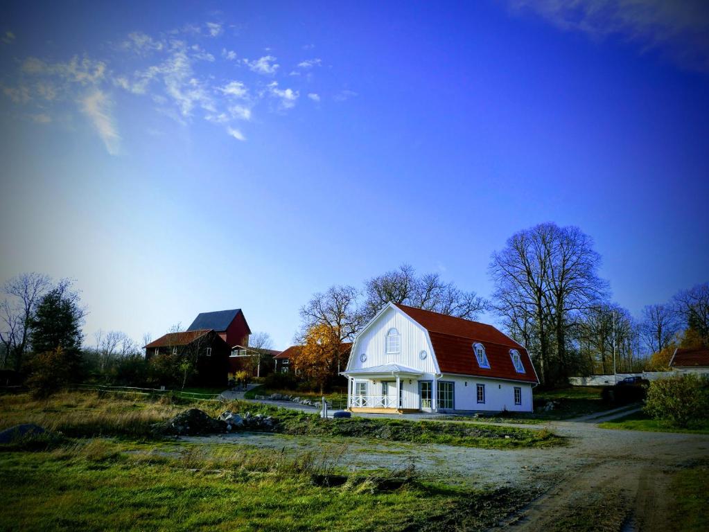 恩雪平Jädra Gårdshotel的一座白色的房子,在田野上有一个红色的屋顶