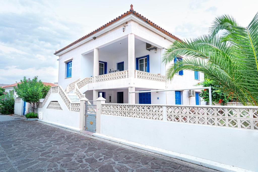 斯卡拉埃雷索La Skala Eressos Holiday Apartments的白色的房子,有白色的围栏和棕榈树