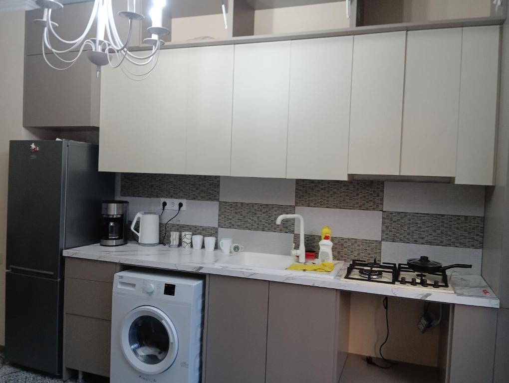 第比利斯თეა的厨房配有白色橱柜和洗衣机。