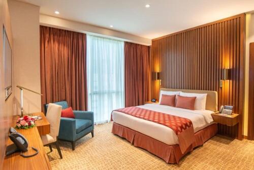 多哈多哈世纪大酒店的酒店客房带一张大床和一把椅子