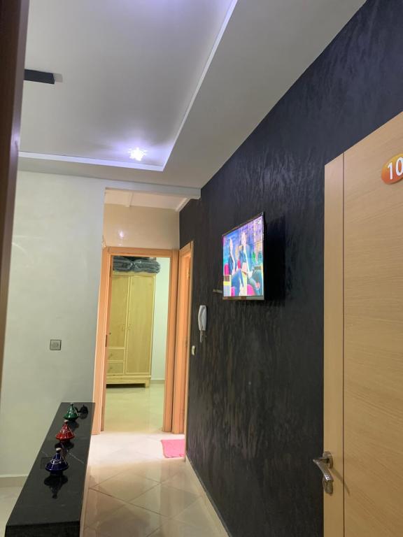 乌季达Appartement cosy et pratique的走廊上设有黑色墙壁,上面配有电视