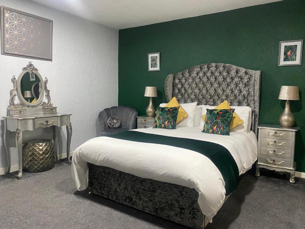 吉夫诺克Saphire Glasgow Apartments的一间卧室设有一张大床和绿色的墙壁