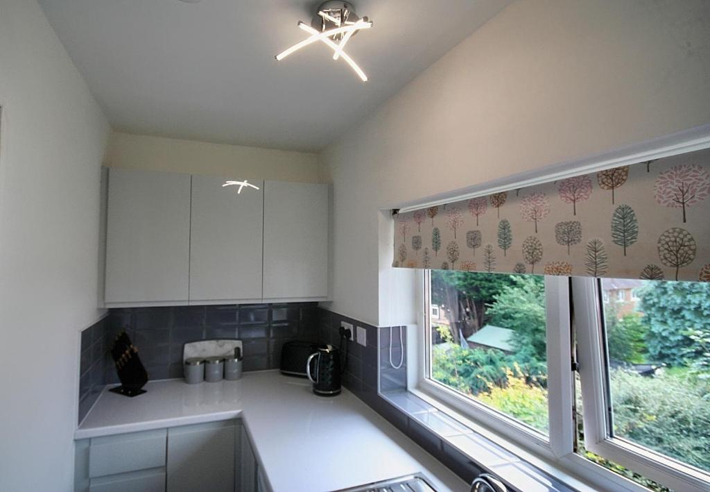 GreenhillSheffield serviced apartment的厨房配有白色橱柜、窗户和水槽