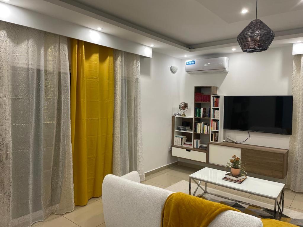 MtsamboroLe Lointain的客厅配有电视和黄色窗帘