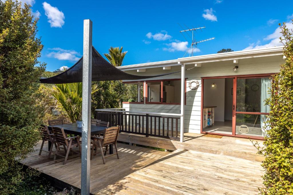 欧尼坦基Onetangi Beach Retreat - Waiheke Holiday Home的房屋内带桌椅的甲板