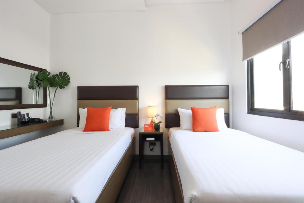 马尼拉Privato Makati的配有白色和橙色枕头的客房内的两张床