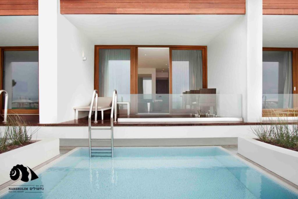 纳奇施里姆Nachsholim Beach Hotel的房屋设有1个带桌椅的游泳池