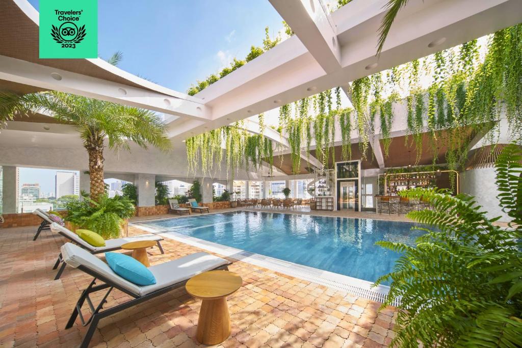 胡志明市Silverland Mây Hotel的一座室内游泳池,位于一座带椅子和植物的建筑中