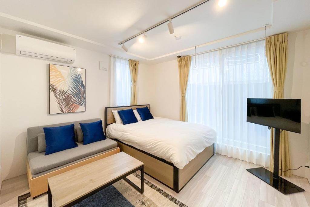 东京Quador Waseda的一间卧室配有一张床、一张沙发和一台电视