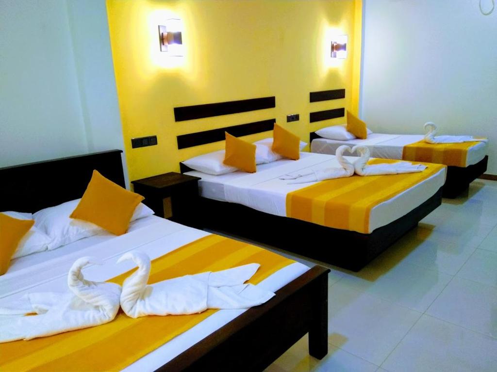 锡吉里亚AMRON RESORT SIGIRIYA的黄色和白色的客房内的两张床