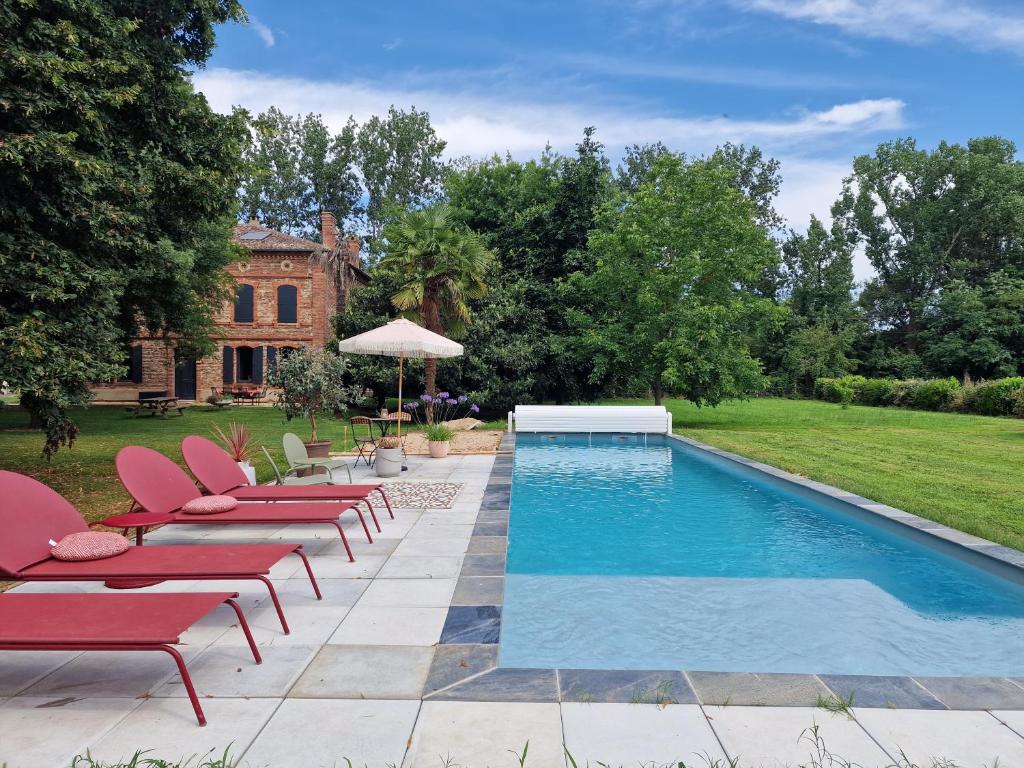 蒙托邦Chambre de charme dans maison de maître的房屋旁的游泳池配有椅子和遮阳伞