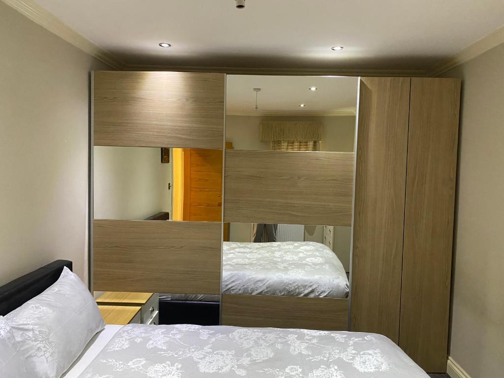 莱斯里普Ruislip Guest House的一间卧室配有一张床和一个大型木制衣柜