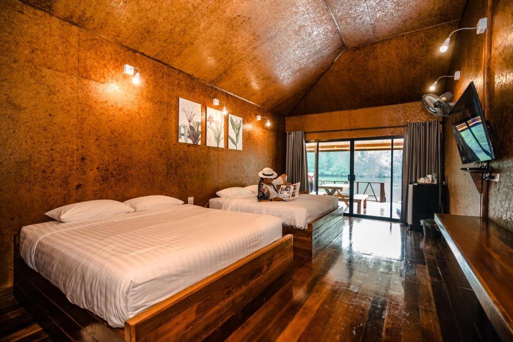 Tha Kradanธารามนตรา รีสอร์ท (Taramontra resort)的一间卧室配有两张床和电视。