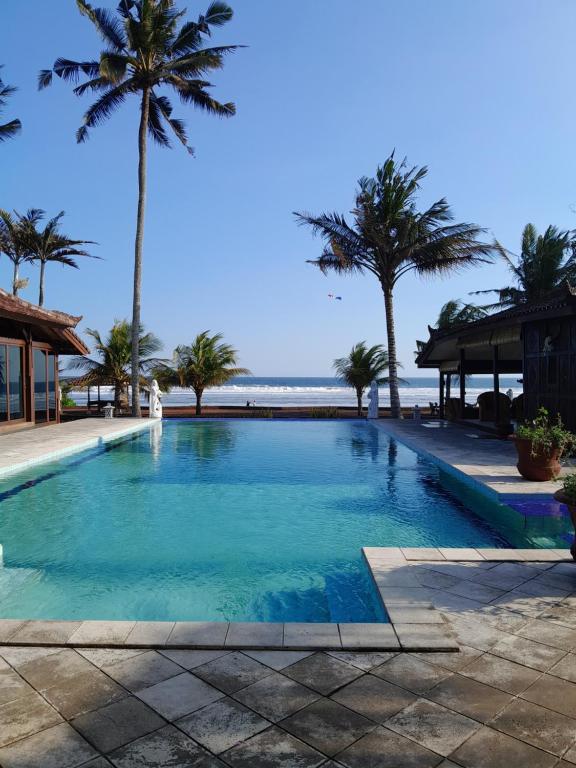 BalianBali Hai Island Resort的棕榈树海滩旁的游泳池
