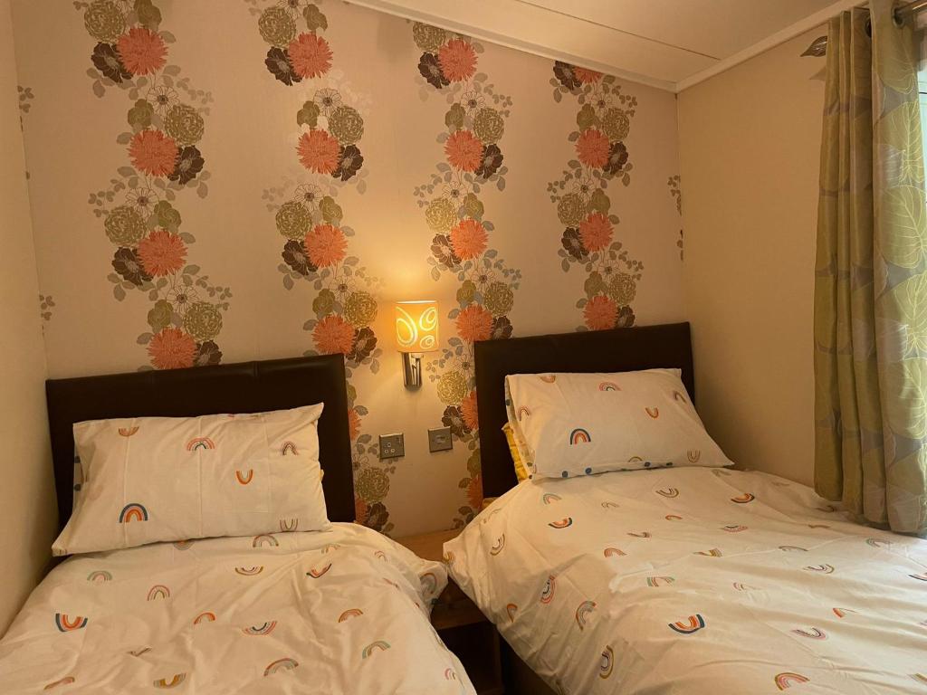 纽顿3 Bedroom Lodge - Willows 24, Trecco Bay的卧室配有两张床,墙上有灯