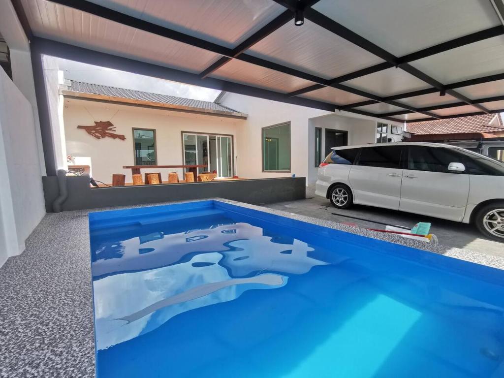 居林Kulim Mini HomeStay的一辆白色的汽车停在一个拥有蓝色泳池的车库里